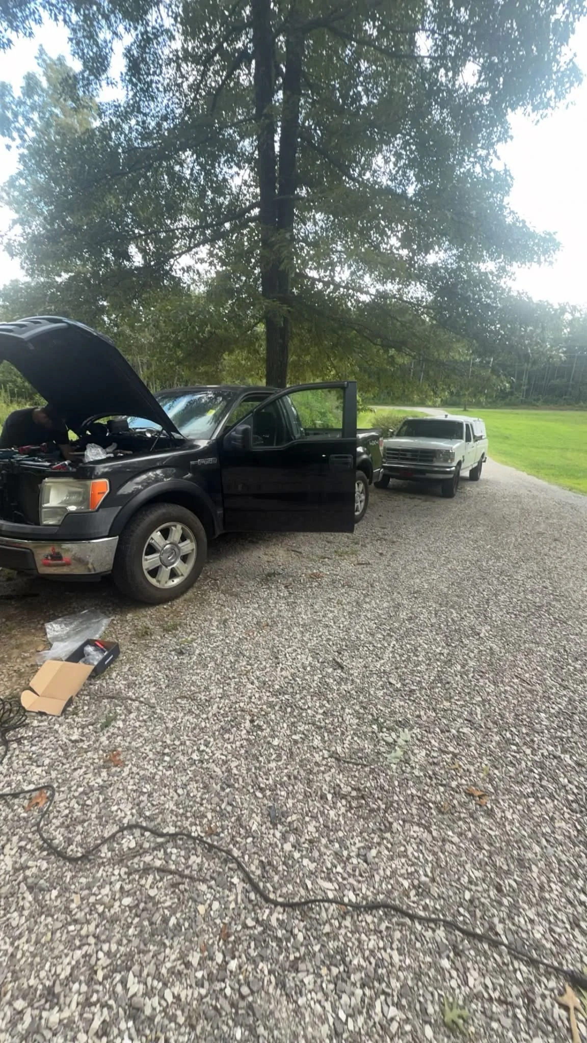 Mobile mechanic working on a black pickup truck in a driveway