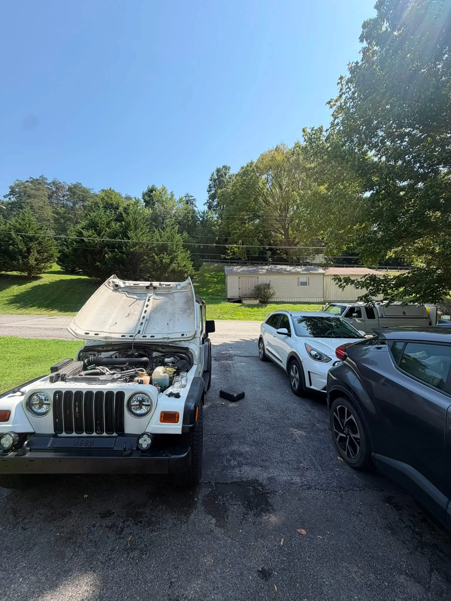 White Jeep being serviced with a mobile mechanic truck nearby