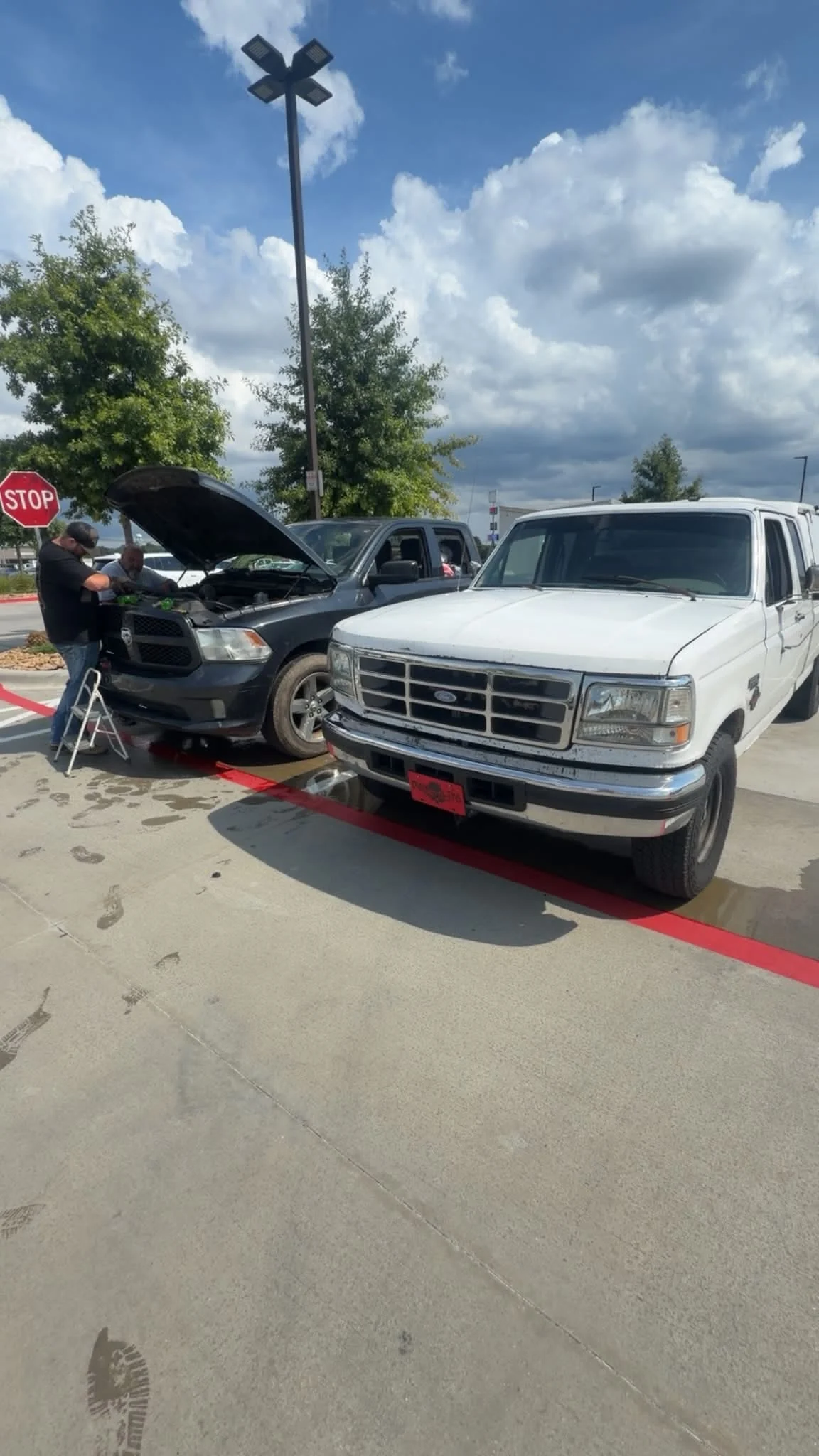 Mechanics performing mobile under-hood repair in a parking lot