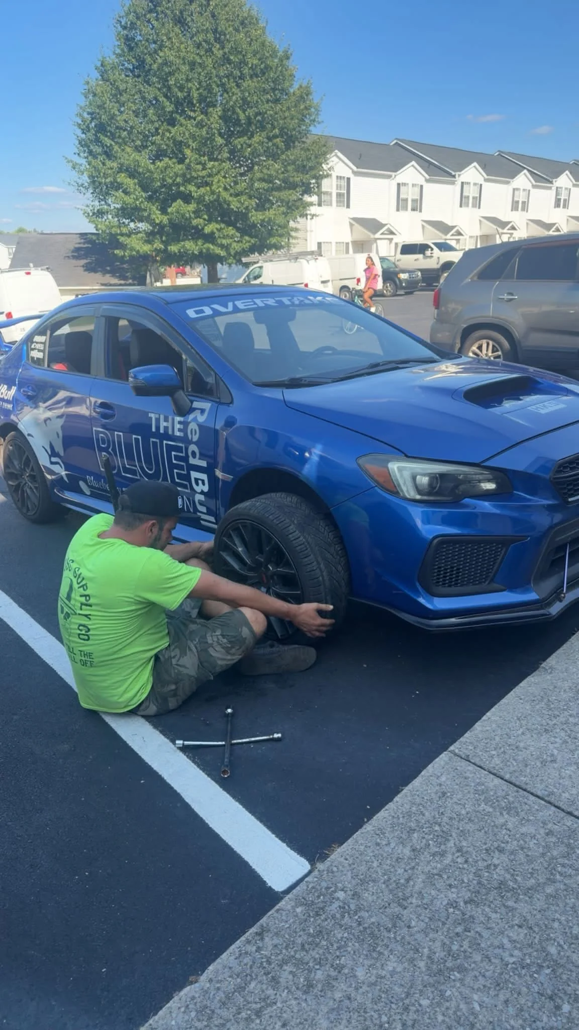Mobile mechanic servicing a wheel on a blue performance car